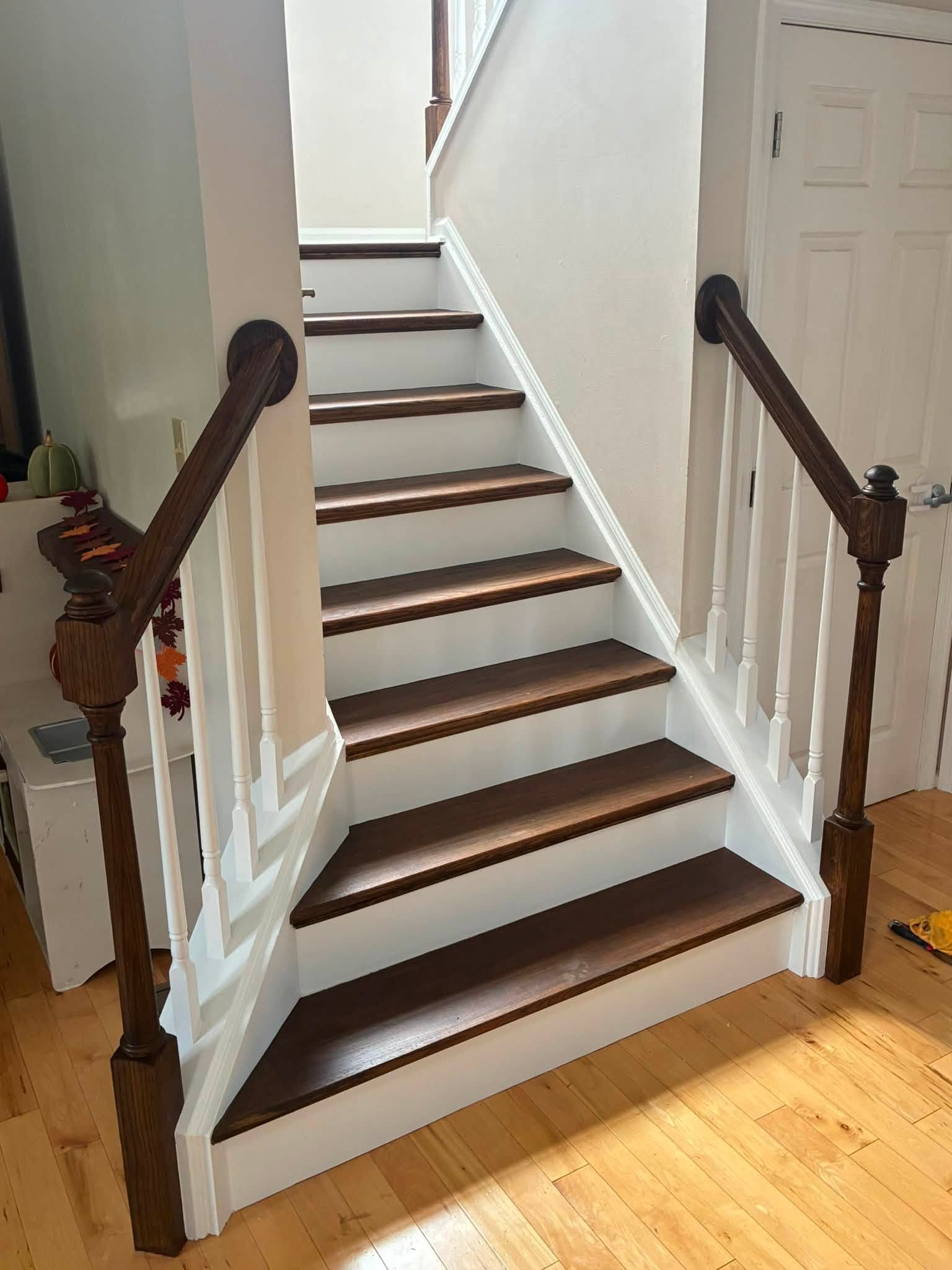 Finished staircase with stained wood treads, white risers, and dark handrails