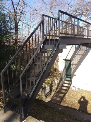 Exterior stair and railing finish work on the side of a building